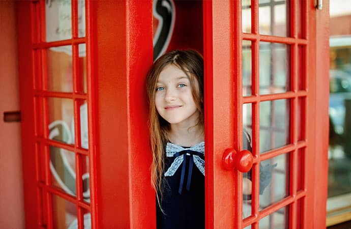 Écolière dans cabine téléphonique Londres pendant un séjour découvertes