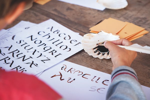 enfant classe découverte en atelier calligraphie avec un calame
