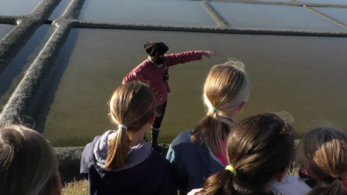 saunier parle aux élèves en anglais lors d'une visite des marais salants